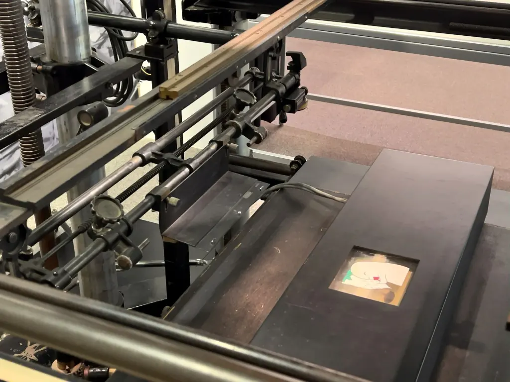 Traditional animation filming desk with stacked sample cels and registration equipment