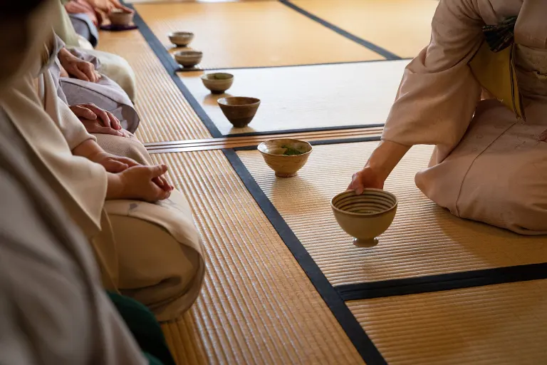 Host in a kimono serving matcha during a Japanese tea gathering