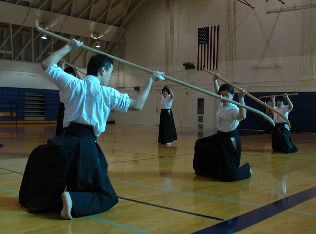 Naginata practitioners holding long training weapons in a coordinated demonstration pose