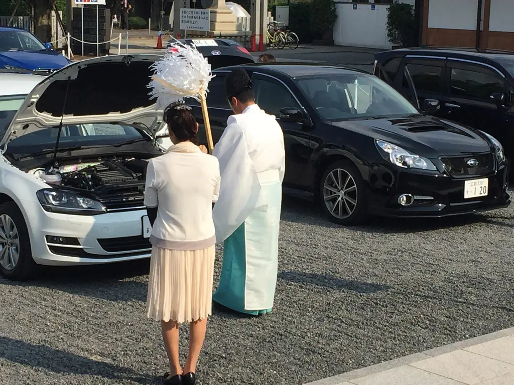 Shinto priest waving a white-paper ōnusa during a vehicle purification in Hiroshima