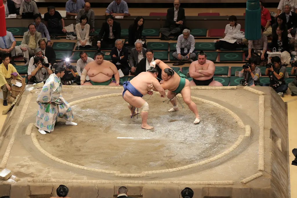 Two professional Sumo wrestlers grappling on the dohyo at Ryogoku Kokugikan