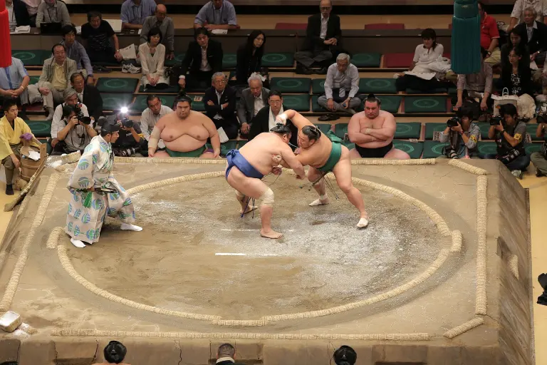 Two professional Sumo wrestlers grappling on the dohyo at Ryogoku Kokugikan