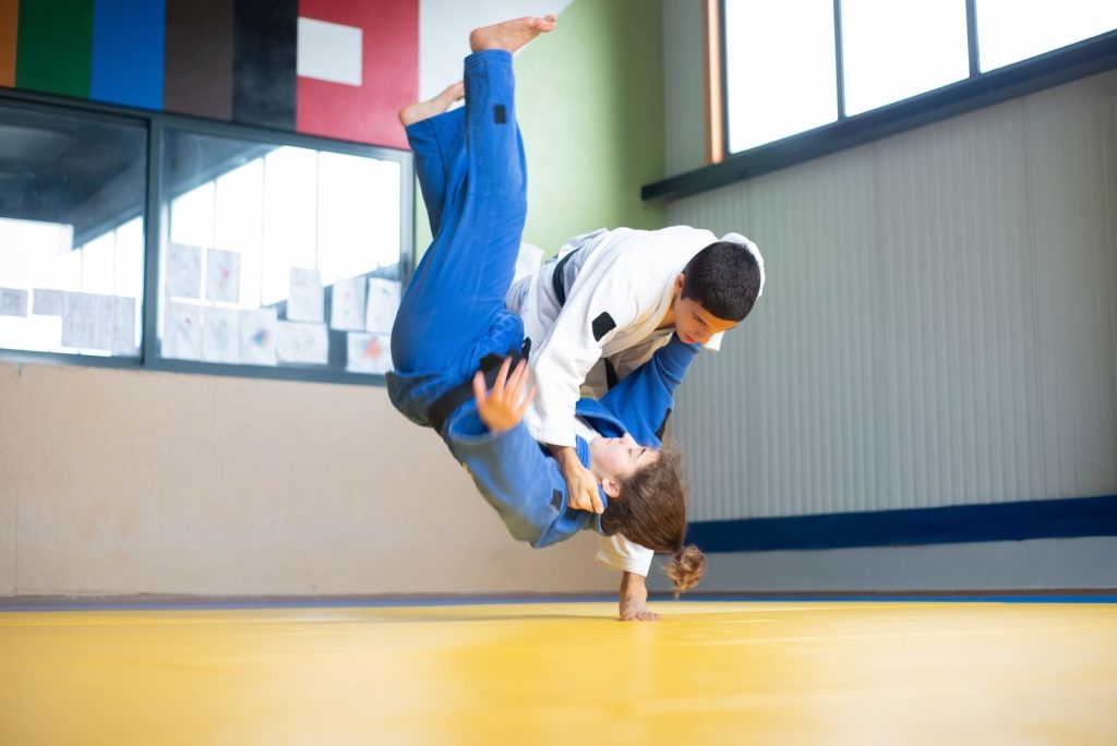 Two judoka practicing a dynamic throw on a tatami mat