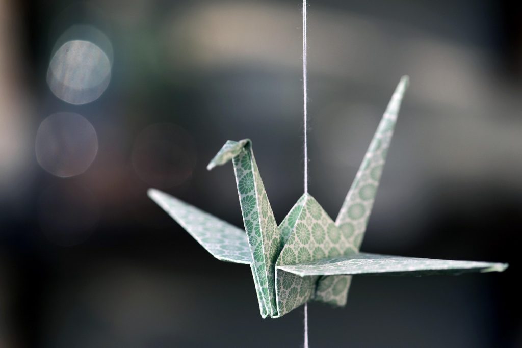 A patterned paper origami crane suspended against a dark background