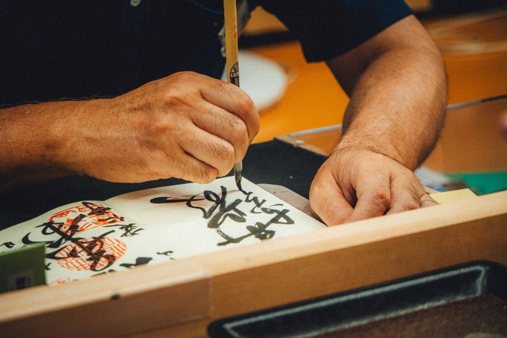 Close-up of an artist writing Japanese calligraphy with ink and brush