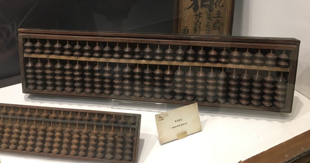 Traditional Japanese soroban abacuses displayed in a museum case