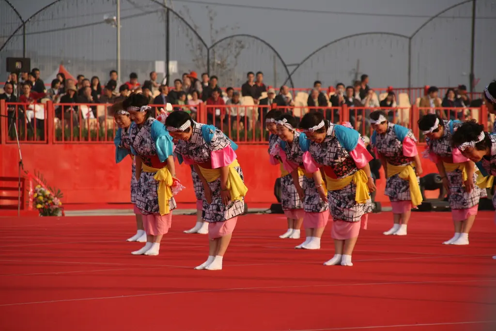 A group of Japanese performers bowing together in front of an audience