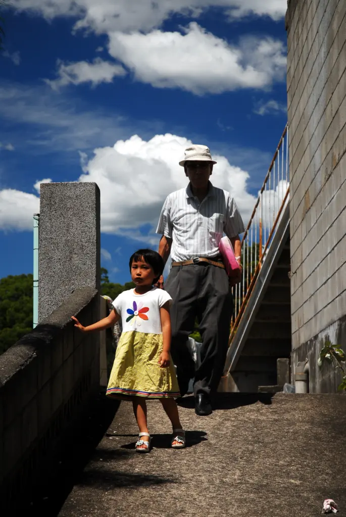 Older Japanese man standing with his granddaughter in Nagasaki