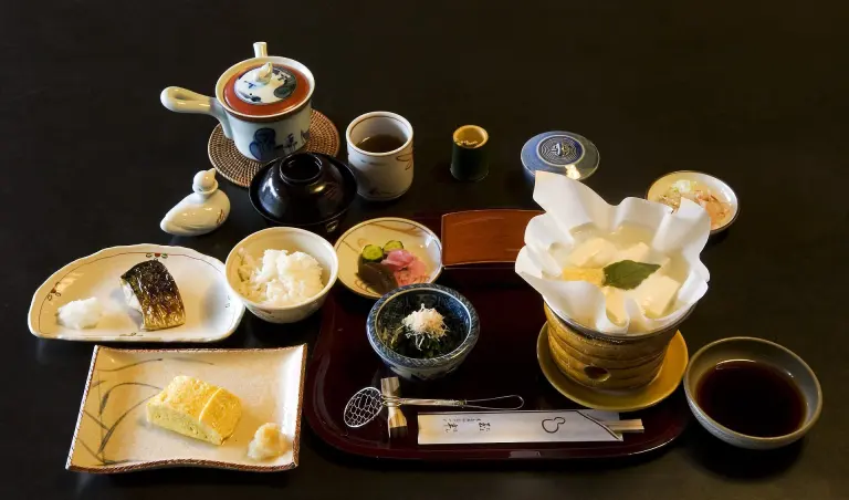 Japanese breakfast arranged in multiple bowls and dishes on a low table