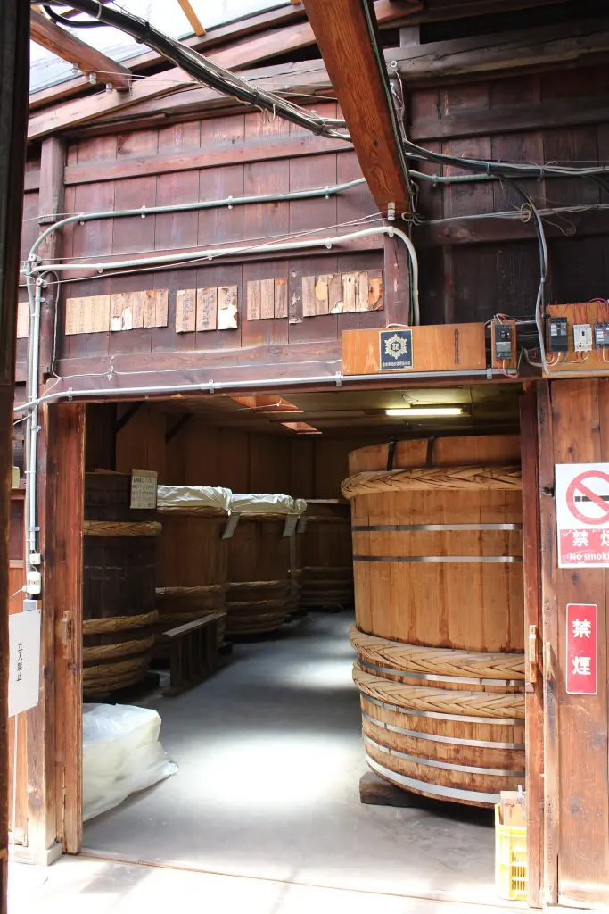 Rows of tall wooden vats inside a traditional miso brewery
