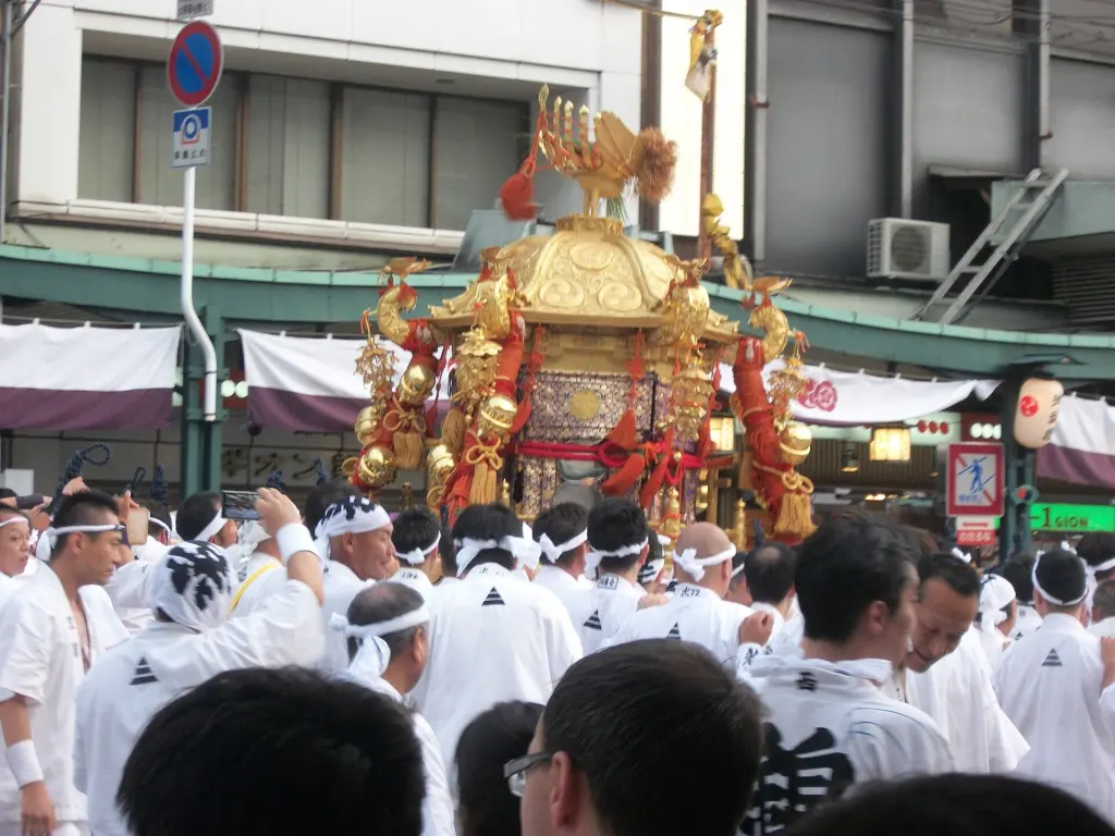 Tall wooden festival float decorated with textiles moving through a Kyoto street
