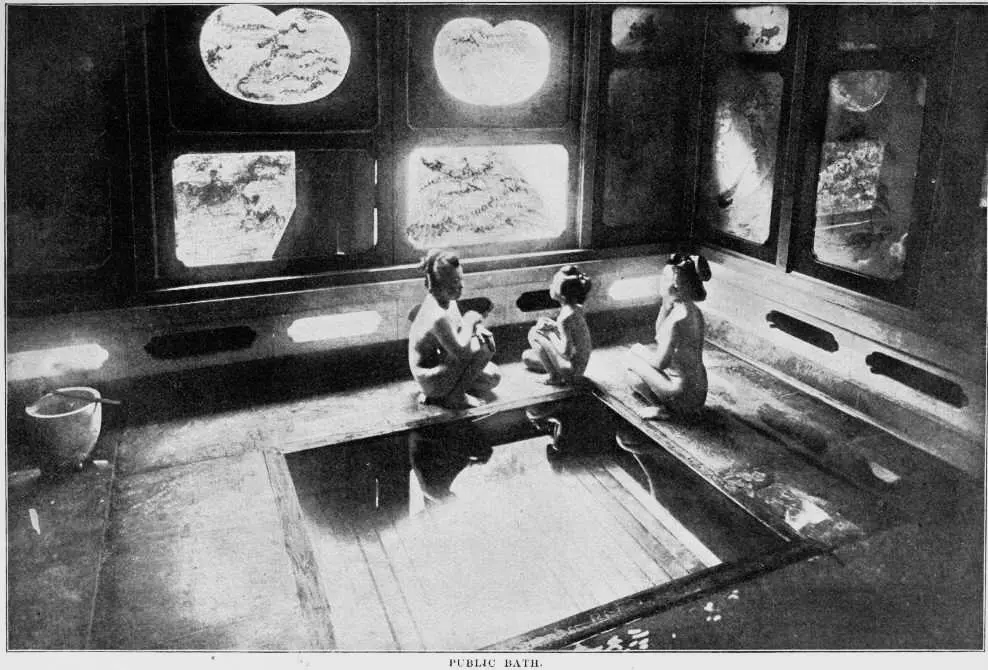 Historic black-and-white view of bathers seated beside a Japanese public bath