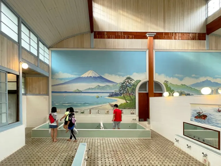 Historic Japanese public bath interior with tiled tubs and a Mount Fuji mural