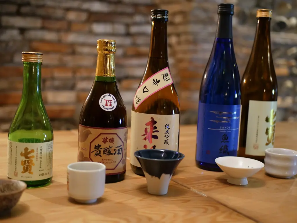 Several Japanese sake bottles and small drinking glasses on a table