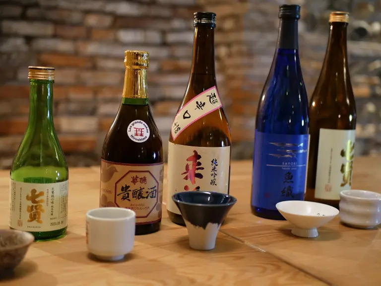 Several Japanese sake bottles and small drinking glasses on a table