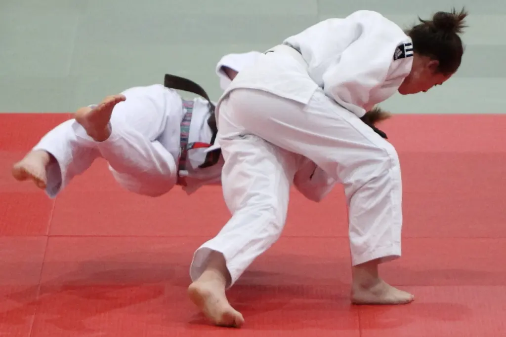 One judoka lifting another during a throw on a competition mat