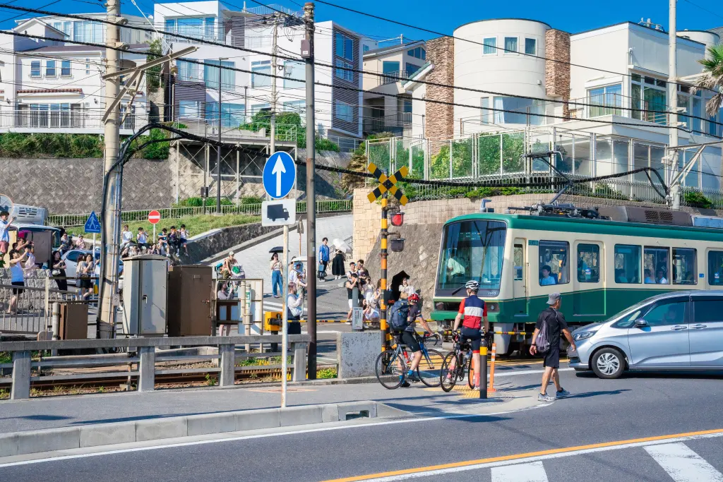A railway level crossing beside Kamakura High School with sea and sky visible beyond the tracks