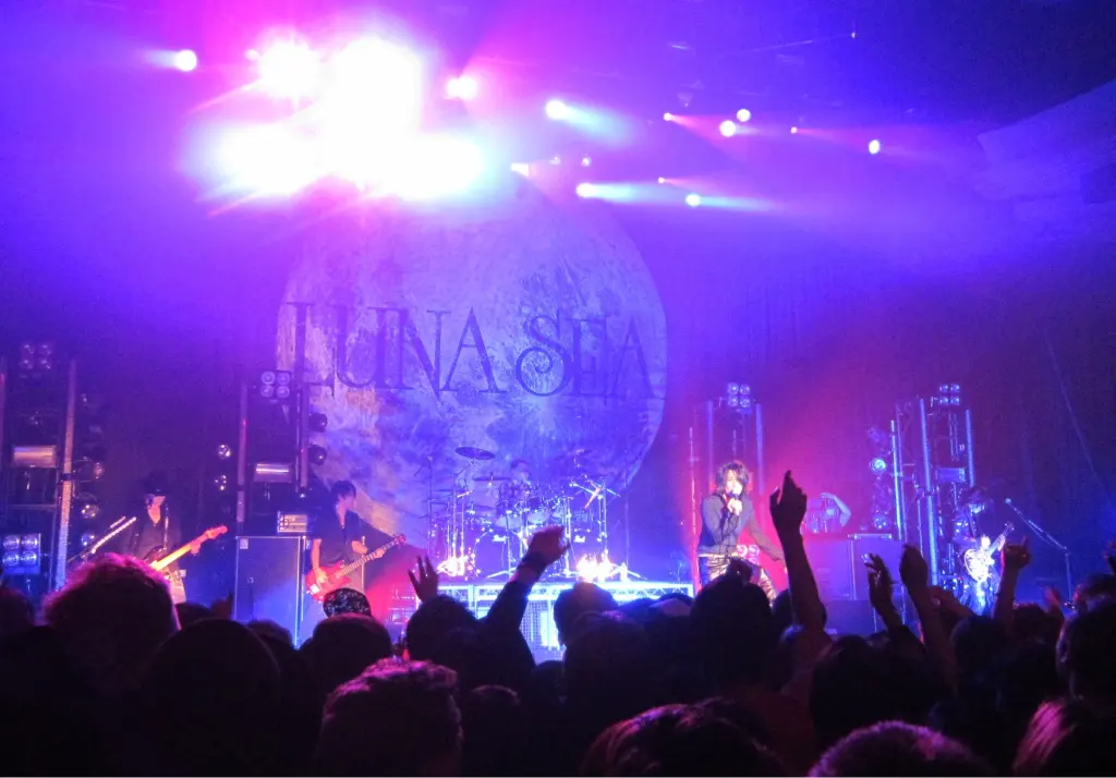 LUNA SEA perform under purple and blue lights at the Hollywood Palladium with the band's moon backdrop behind them