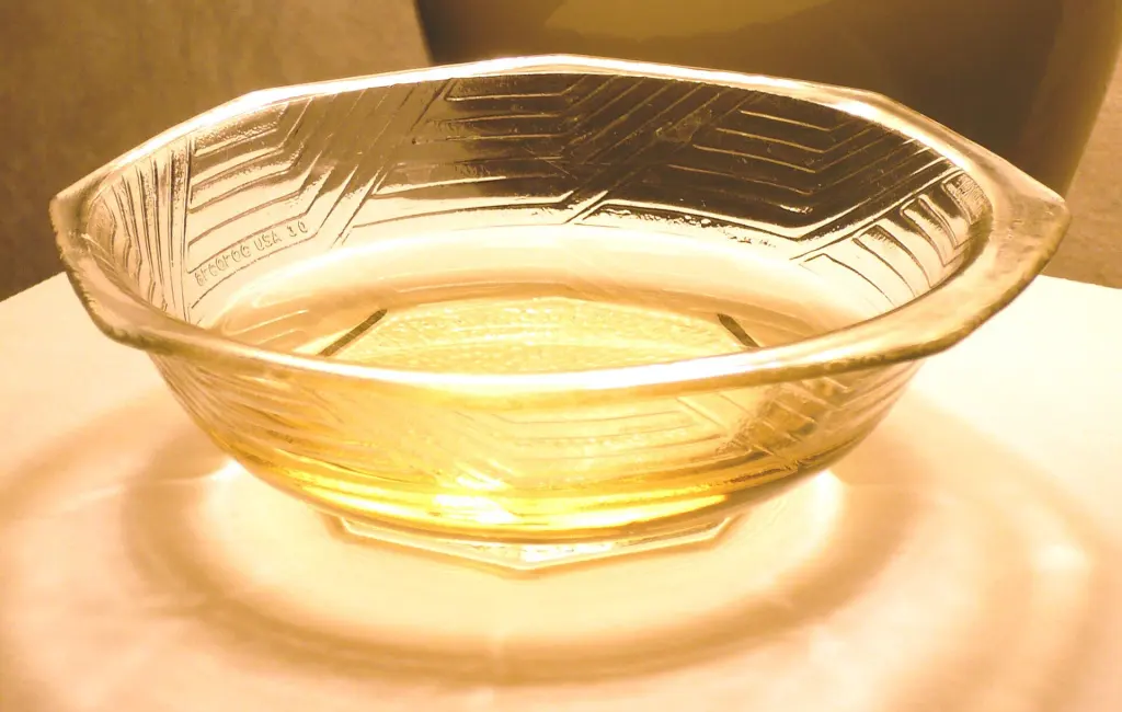 A shallow white bowl filled with amber-colored mirin