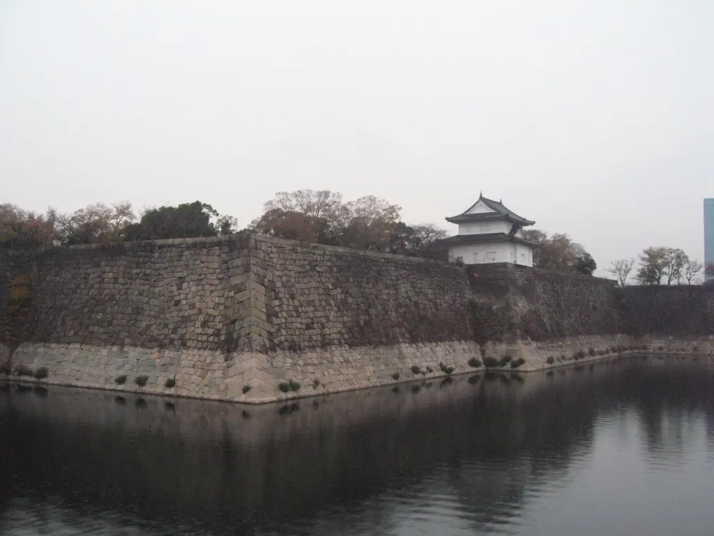 Osaka Castle’s stone walls and a white turret beside the moat.