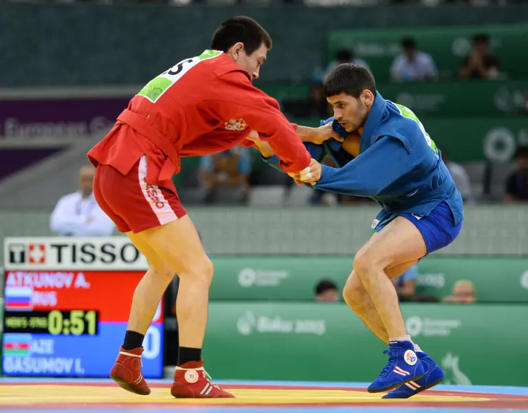 Two Sambo athletes in red and blue jackets grappling during the 2015 European Games