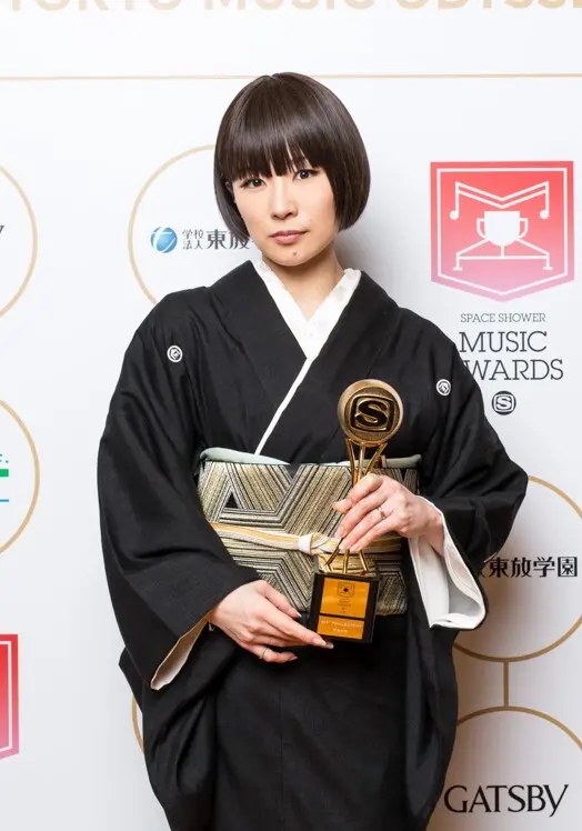 Shiina Ringo stands in a black kimono holding a music award trophy at the 2016 Space Shower Music Awards