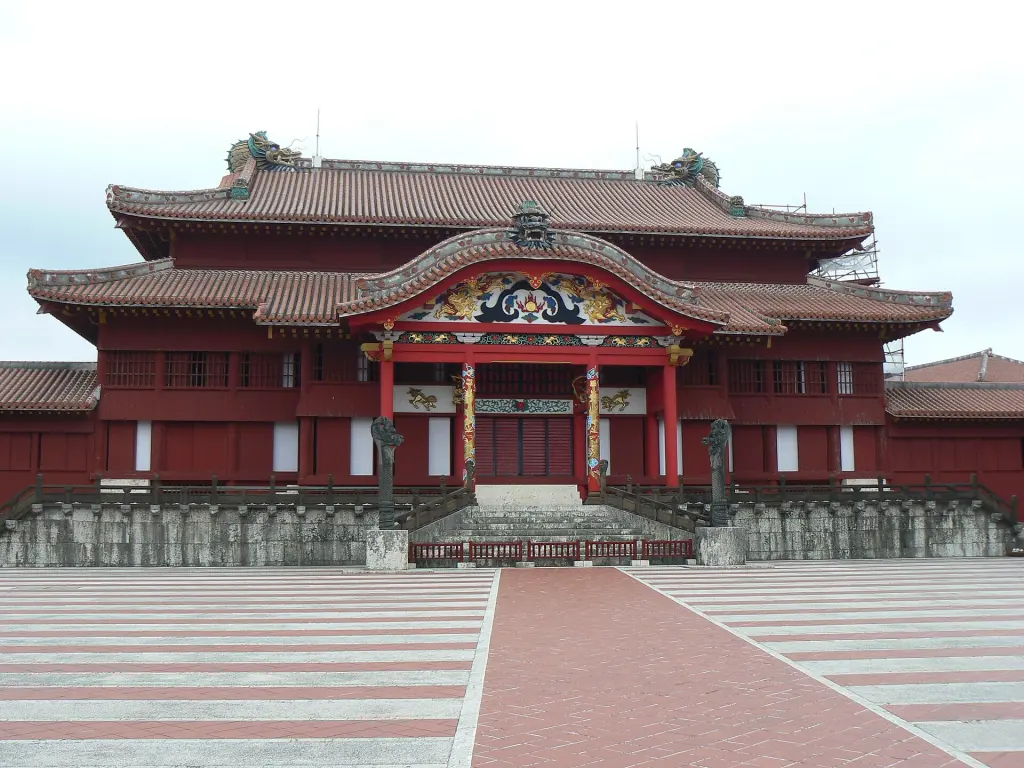 Red main hall and courtyard of Shuri Castle under a blue sky