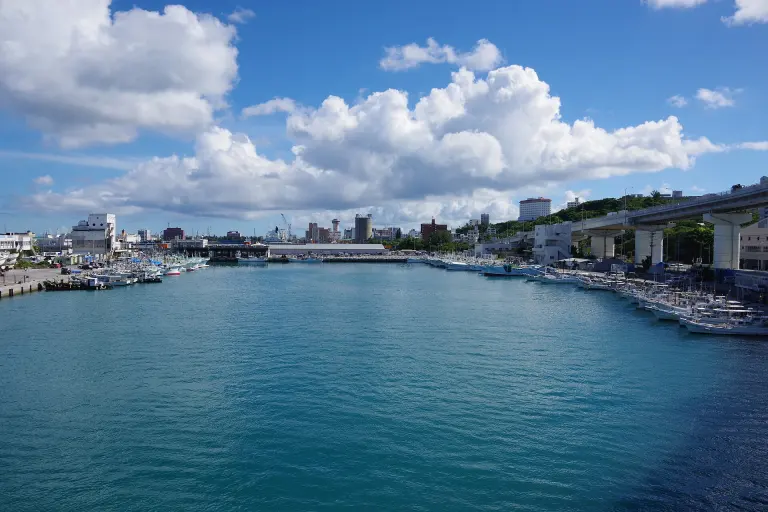 Tomari Fishing Port in Naha with harbor water, boats, quays, and city buildings