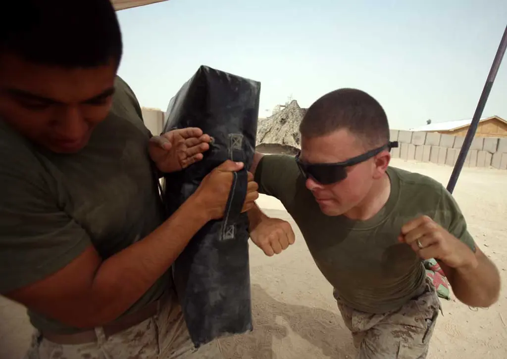 A U.S. Marine delivering a horizontal elbow strike into a training pad held by another Marine