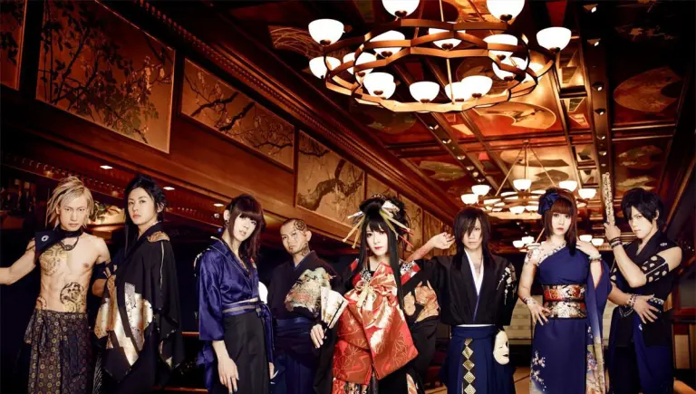 The eight members of Wagakki Band pose in elaborate stage costumes inside a richly decorated interior