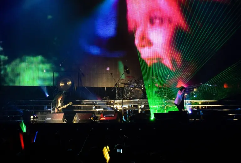 X Japan perform on a large concert stage in Hong Kong with coloured lasers and an image of hide on the screen