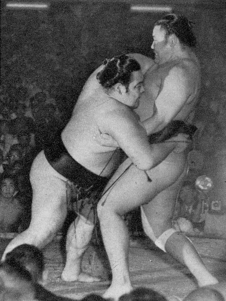 Two sumo wrestlers at the edge of the ring during a yorikiri force-out