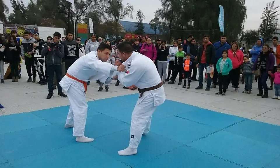 Two judoka in white judogi practising randori on a training mat