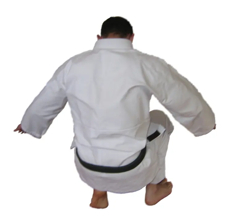 A practitioner on a mat demonstrating the final position of a backward Judo breakfall