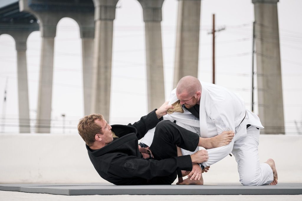 Two Brazilian jiujitsu practitioners grappling on an outdoor mat