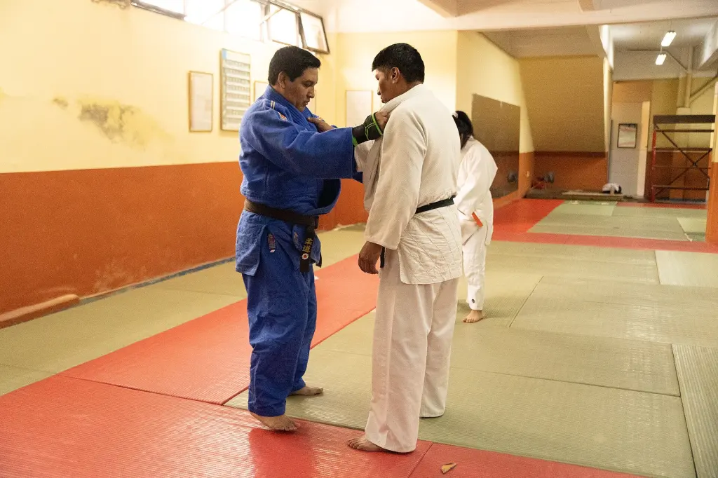 Two judoka practise a sleeve-and-lapel grip on a tatami